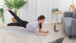 © Pichsakul - Yoga exercise concept, Young Asian woman doing plank pose and watching yoga tutorial on laptop