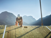 Carpenter Working On Roof In Front Of Mountains