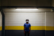 © Westend61 - Young man wearing astronaut helmet standing in front of wall at underground walkway