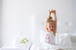 © Westend61 - Little girl stretching arms sitting in bed