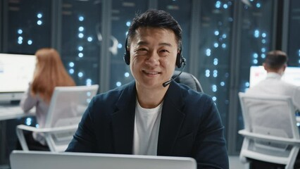 Wall Mural - portrait young asian it developer administrator wearing headset speaker using laptop computer lookin