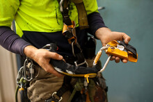 Rope Access Inspector Inspecting Self Controlled Stop A Fall Descent Safety 
Device With Absorbing Lanyard Attached  Prior To Use Clipping Into Chest Harness Loop  
