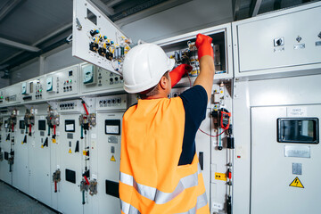 Wall Mural - Adult electrician builder engineer testing and screwing equipment in fuse box and repairing of modern electricity power station using voltmeter. Automatic control cabinet