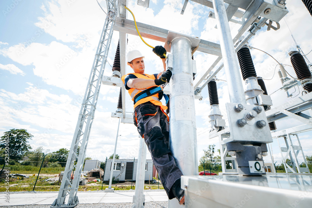 Electrician in protective helmet working on high voltage power lines ...