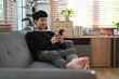 © Prathankarnpap - Man in warm sweater resting on couch and using smart phone, enjoying leisure weekend time at cozy home