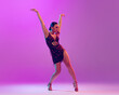 Leinwandbild Motiv Smoothness and accuracy of movements. Young graceful flexible woman dancing ballroom dance without partner isolated on purple background.