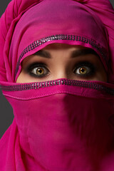 Wall Mural - Close-up shot of a young charming woman wearing the pink hijab decorated with sequins. Arabic style.