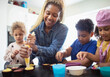 © Caia Image - Happy mother and kids decorating cupcakes in kitchen