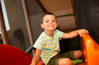 Cheerful smiling six-year-old boy in the children's play center on the top of the slide