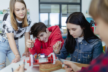 Wall Mural - group of high school students building and programming electric toys and robots at robotics classroo