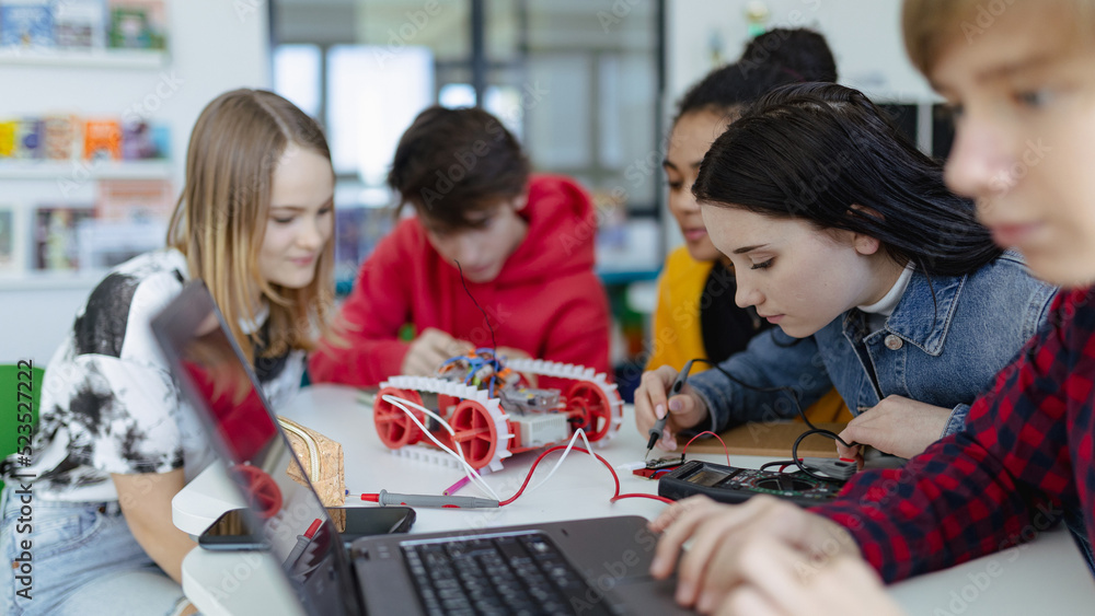 Group of high school students building and programming electric toys ...