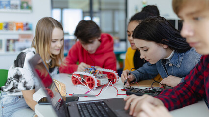 Wall Mural - group of high school students building and programming electric toys and robots at robotics classroo