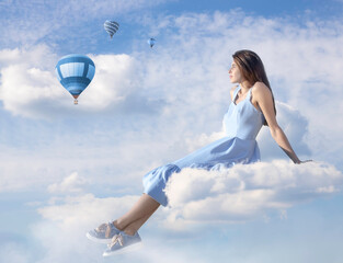 The girl is sitting on a cloud against the background of a blue sky with clouds. Balloons are flying in the background