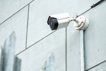 Small CCTV Digital Camera Mounted On A Wall In Focus. Metal Fence With Spike Out Of Focus. Security Industry.