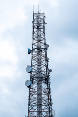 Tall metal mast to broadcast 4g and 5g signal. Mobile phone and internet provider. Vertical image. Cloudy sky background.