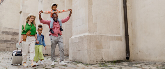 Sticker - Multiracial family travel together with suitcases, walking in old city centre.