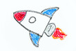 Colorful oil pastel hand drawing in spaceship or rocket shape on white paper background