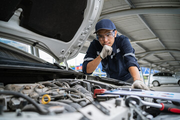 Wall Mural - Portrait of an Asian mechanic checking the safety of a car. Maintenance of damaged parts in the garage. Maintenance repairs. Repair service concept.