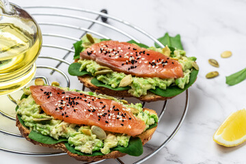 Wall Mural - Delicious breakfast or snack sandwich salmon, avocado, spinach, nuts, sunflower seeds, toast with red fish and guacamole. Healthy, clean eating. Vegan or gluten free diet. top view, copy space