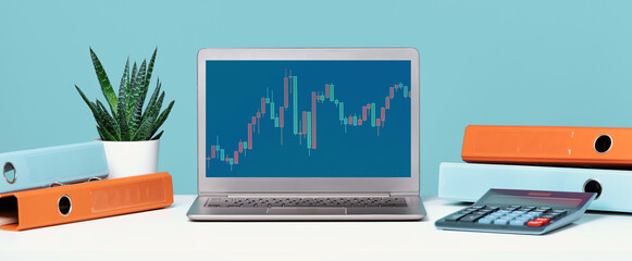 Stock exchange trade forex financial concept. Laptop with graphs headset on white desk with calculator anf folders. Distant learning or broker working from home, online courses or video call concept.