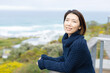 © Wavebreak Media - Portrait of happy asian woman wearing jumper and leaning on balcony alone