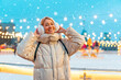 © Andrii - Wintertime. Christmas holiday evening, woman standing outside and smile. Christmas illumination and decoration background. Winter holiday season.