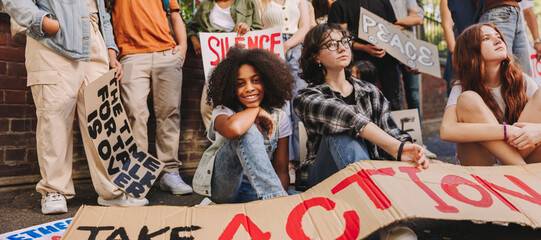 Wall Mural - Cheerful teenage girl sitting with a group of youth peace activists