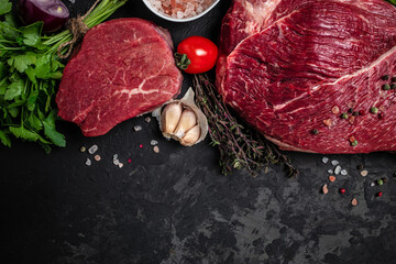 Two fresh raw beef steaks with spices ready to cook on a dark background. Culinary, cooking, concept. banner, menu, recipe place for text, top view