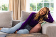 © WavebreakMediaMicro - Smiling caucasian woman sitting on couch in sunny living room