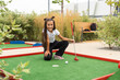 © Angelov - Miniature golf outdoor. Little caucasian girl golfing in the mini golf course.