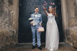 Stylish happy bride and groom throwing candy on background of church after holy matrimony. Wedding ceremony in cathedral. Beautiful emotional spiritual wedding couple with sweets