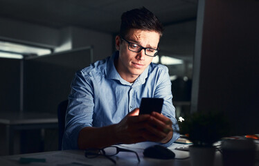 Leinwandbilder - Confused businessman texting on his phone at the office at night. Handsome, confident and corporate caucasian male looking at messages from coworkers while working overtime and feeling unsure