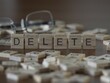 © lexiconimages - delete word or concept represented by wooden letter tiles on a wooden table with glasses and a book