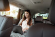 © Dmytro - Young business woman with a modern laptop sitting in the back seat of luxury car. Successful startup, distance working, female boss concept.
