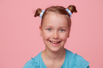 Portrait of cute toddler girl child with two funny tails over pink background. Advertising childrens products. Funny face