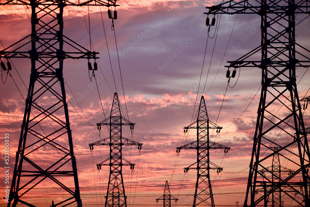 High voltage power lines pylons and electrical cables on a sunset sky ...
