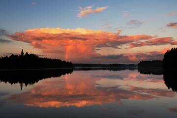 Wall Mural - anvil cloud lit by the setting sun. cumulonimbus cloud rising over landscape in summer. cloud reflec