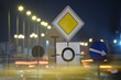 Leinwandbild Motiv Roundabout road signs with blurred cars on city street traffic at night. Urban transportation concept
