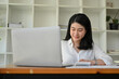 © bongkarn - Successful Asian businesswoman at her office desk managing her task on laptop.