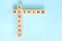 Rethink And Rebrand Business Concept. Wooden Blocks Crossword Puzzle Flat Lay In Blue Background.	
