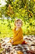 Adorable toddler girl sitting on the ground and having picnic in autumn park. Happy kid enjoying fall day. Outdoor activites for kids