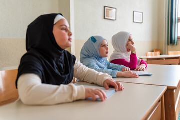 Wall Mural - Group of children Muslim girls in hijab sitting at the school desk in the classroom during the class.