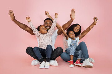 Wall Mural - Family fun. Young african american parents spending time with their little daughters with open arms, laughing together over pink background, banner, panorama, copy space.