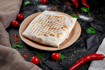 Wall Mural - Shawarma, pita pie, stuffed with chicken, beef and herbs on a dark stone table. Fast food and delivery restaurant concept. Covered bun.