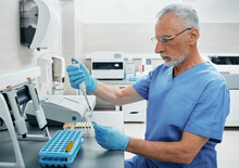 Mature Male Scientist With Micropipette For Test Analyzes Working At Medical Research Laboratory. Laboratory Technician Determines Person's Blood Type