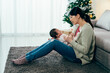 © PR Image Factory - full length asian millennial mom sitting on rug is coaxing her child with verbal soothing. japanese lady trying to calm her crying baby who’s lying on her legs. authentic lifestyle