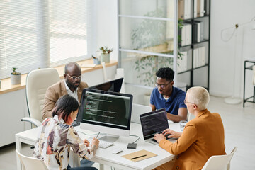 High angle view of Group of programmers working on computer and laptop with codes during teamwork at office