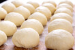 Yeast dough balls on the wooden board with flour. Preparing to bake buns, pizza or bread