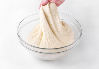 Wall Mural - Kneading yeast dough in glass bowl on white table