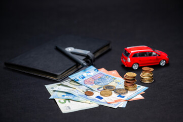 euro cash, notebook with pen and red toy car on black background, insurance and loan concept